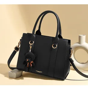 Détails du sac en cuir noir avec motif litchi, finitions dorées et pendentif d'ours
