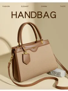 Detail einer Handtasche aus braunem Leder und Khaki-Canvas mit goldenem Logo und Gurt