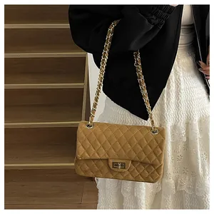 Detailed close-up of brown quilted suede texture and golden twist-lock on flap bag