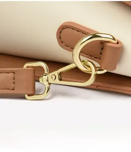 Détail du fermoir mousqueton doré et de la bandoulière en cuir marron du sac à main