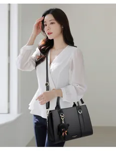 Détail du sac à main en cuir noir avec finitions dorées et pendentif petit ours