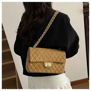 Rear view of a model wearing a brown quilted velvet crossbody bag with gold chain strap