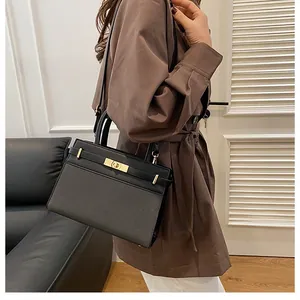 Detail of black textured handbag with golden hardware and buckle on a brown coat model