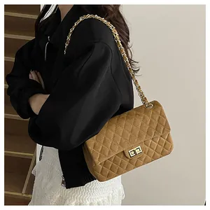 Detailed view of brown quilted velvet crossbody bag with gold chain strap on model