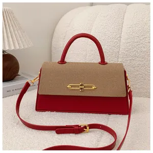 Detail der Handtasche aus rotem Leder und beigem Canvas mit eleganter goldener Schließe