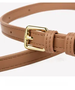Gros plan d'une ceinture fine en cuir marron clair avec boucle dorée rectangulaire