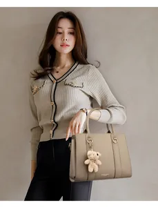Sac à main élégant en cuir kaki avec un porte-clés ours en peluche porté par un mannequin
