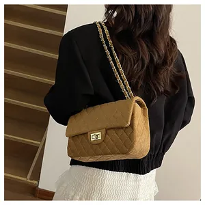 Detail of vintage brown suede crossbody bag with quilted pattern and gold metal clasp