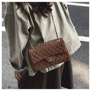 Close-up of quilted pattern and gold lock on brown shoulder bag with chain strap