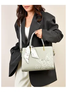 Détail du sac cabas gris-vert avec broderie papillon blanche et foulard décoratif