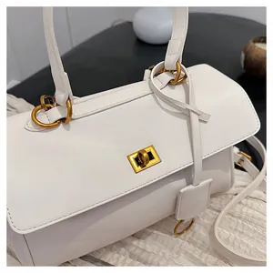 Detail of white leather handbag showing gold twist lock and smooth texture finish