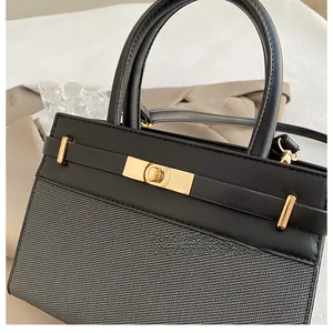 Detail of black textured handbag featuring iconic gold twist lock and leather strap accents