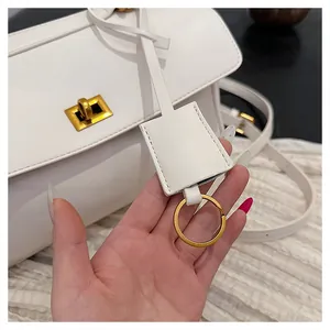 Detailed view of white leather tote with gold twist lock and adjustable shoulder strap