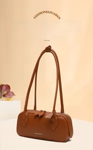 Dettaglio di una borsa baguette in pelle marrone con grana litchi, logo bianco e cerniera