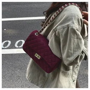 Detail of burgundy velvet quilted bag featuring diamond stitching and metal chain strap