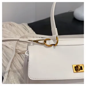 Close-up of vintage gold metal lock and hardware on white leather shoulder bag