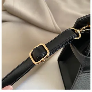 Close-up of black leather bag strap featuring gold metal buckle and lobster clasp