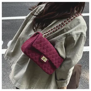 Detailed view of burgundy quilted velvet crossbody bag with golden chain and clasp