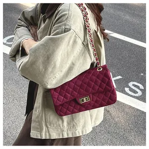 Close-up of burgundy velvet quilted handbag with gold chain strap and turn-lock detail