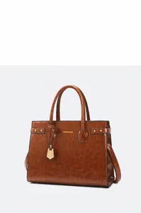 Brown leather handbag detail featuring shiny texture and gold fashion lettering