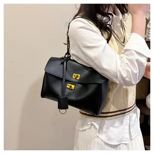 Close-up of black leather shoulder bag with gold twist locks and circular metal ring charm