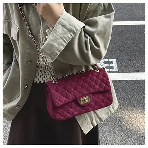 Detail of burgundy velvet quilted bag with gold hardware and metal chain strap