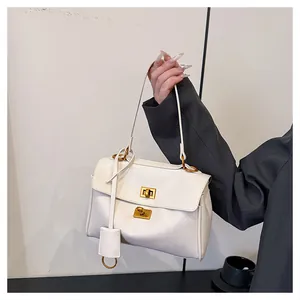 Detail of white faux leather bag with two golden square twist locks and decorative tag