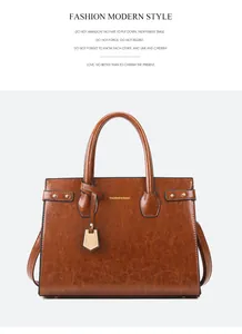 Detail of brown faux leather handbag showing fashion logo and metallic zipper texture