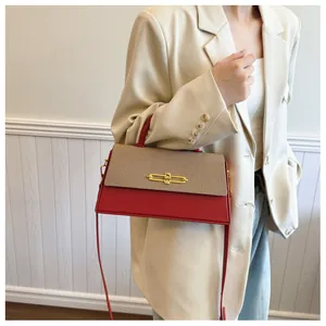 Detail einer roten und beige strukturierten Handtasche mit elegantem Gold-Metallverschluss