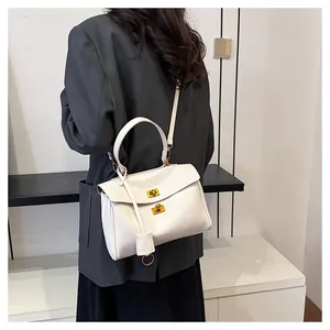 Model wearing a white leather tote bag with gold hardware and a top handle