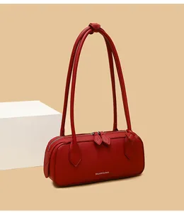 Dettaglio della trama in pelle litchi rossa e logo bianco sulla borsa baguette