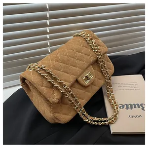 Close-up of brown velvet quilted bag with gold chain strap and metallic twist lock
