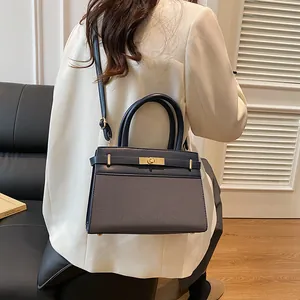 Fashionable dual-tone handbag with gold twist lock and adjustable shoulder strap