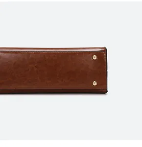 Detailed close-up of brown faux leather bag base featuring gold protective metal studs