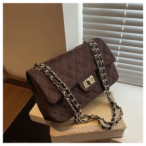 Detail of dark coffee velvet quilted chain bag with elegant gold metal twist lock