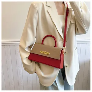 Detail einer schicken Damenhandtasche in Rot und Beige mit einem stilvollen Metallverschluss