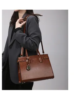 Brown vintage leather handbag with double handles and metallic pendant detail on a model
