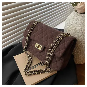 Macro shot of brown quilted velvet crossbody bag with golden chain and luxury texture