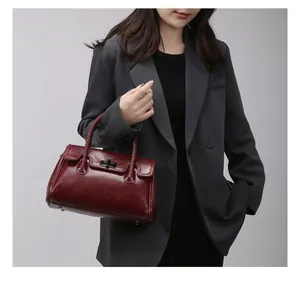 Vue détaillée du sac en cuir bordeaux avec poignée tressée et fermoir rotatif argenté