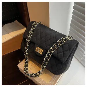 Detailed view of black quilted velvet bag with gold chain and vintage metal lock closure