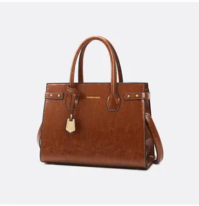 Detailed close-up of caramel brown leather tote bag with gold studs and handle