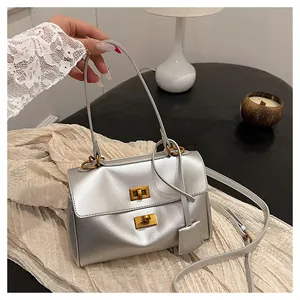 Detail of silver metallic handbag featuring double turn-lock closure and gold hardware
