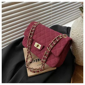 Detail of burgundy velvet quilted bag with gold chain strap and metallic lock closure