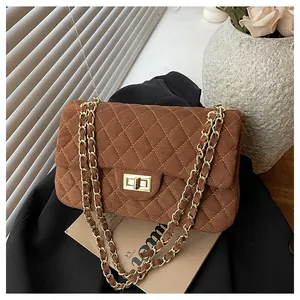 Detail of brown velvet quilted crossbody bag with gold chain strap on blazer