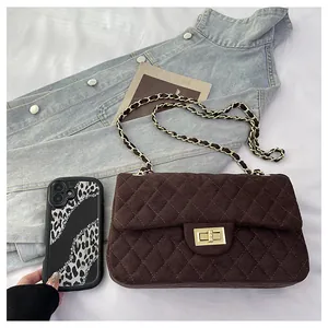 Detail of dark brown quilted velvet bag with gold clasp and metal chain strap