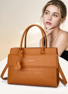 Close-up of caramel embossed crocodile texture handbag with silver logo and leather strap