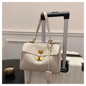 Close-up of cream leather tote bag with gold buckles hanging on luggage handle