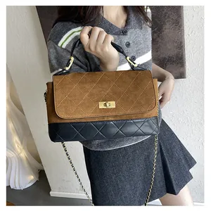 Detail showing brown frosted fabric and black leather stitching on a quilted bucket bag