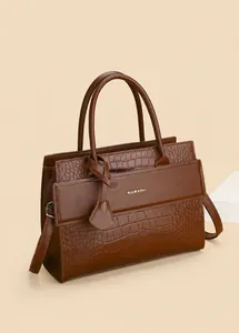 Detail of dark brown embossed crocodile texture on vintage leather handbag with logo
