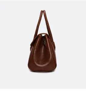 Détail du sac à main en cuir huilé marron avec poignées tressées et crochets métalliques